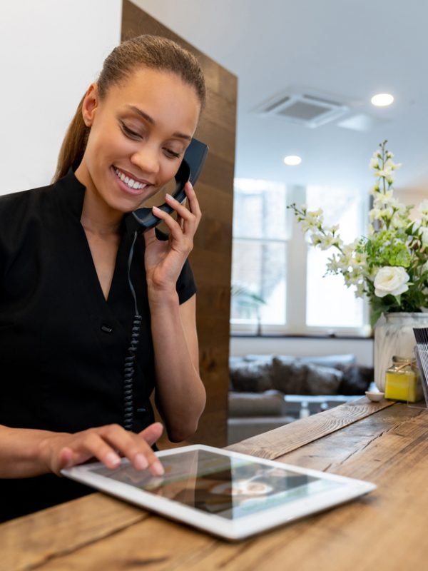 Woman working at a spa talking on the phone and making a booking - small business concepts. ****DESIGN ON SCREEN IS OURS**